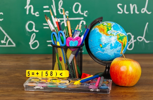 Retour à l'école - tableau noir avec boîte à crayons et équipement scolaire sur table