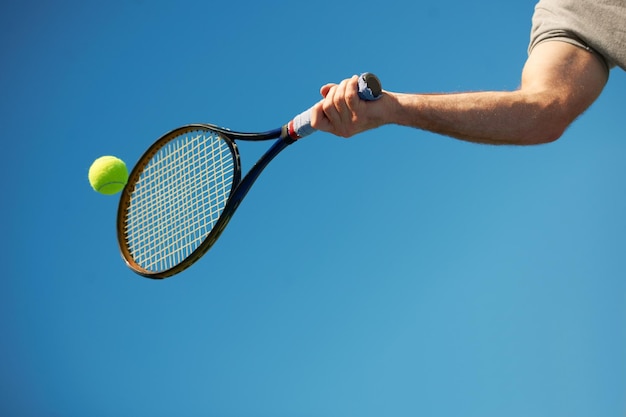 Et retour Plan d'un bras frappant une balle de tennis avec une raquette