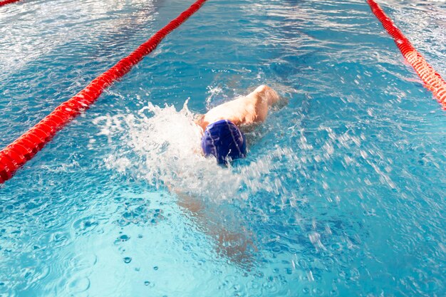 Un retraité de 70 ans se repose et nage dans la piscine dans une piscine bleue propre à l'air frais en vacances