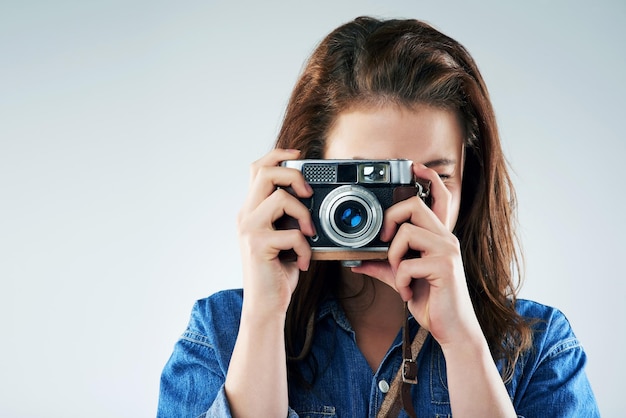 Retro est la voie à suivre Studio portrait d'une jeune femme à l'aide d'un appareil photo vintage sur un fond gris