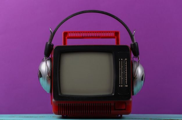 Rétro rouge vieux mini tv portable avec casque sur fond violet.