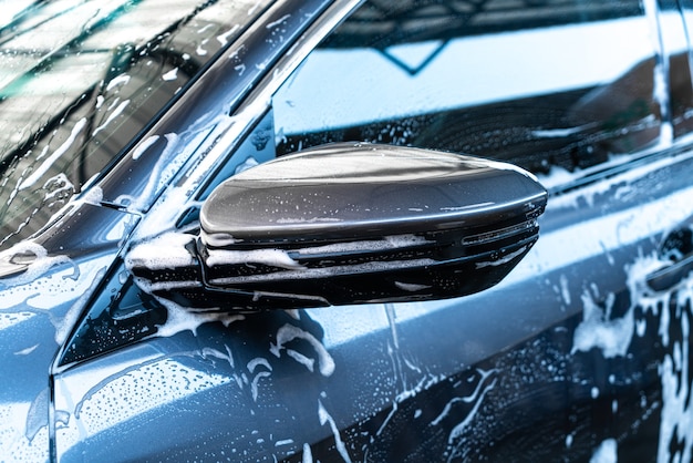 Rétroviseur de voiture close-up avec mousse de lavage de voiture