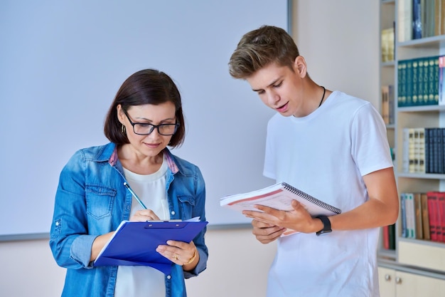 Réunion d'adolescents de gars d'étudiants universitaires discutant avec un mentor enseignant en classe