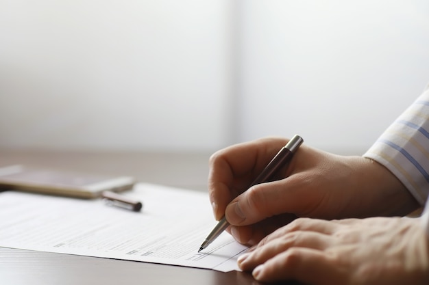 Réunion d'affaires. Un homme signe un contrat. La main masculine avec un stylo prend des notes au bureau.