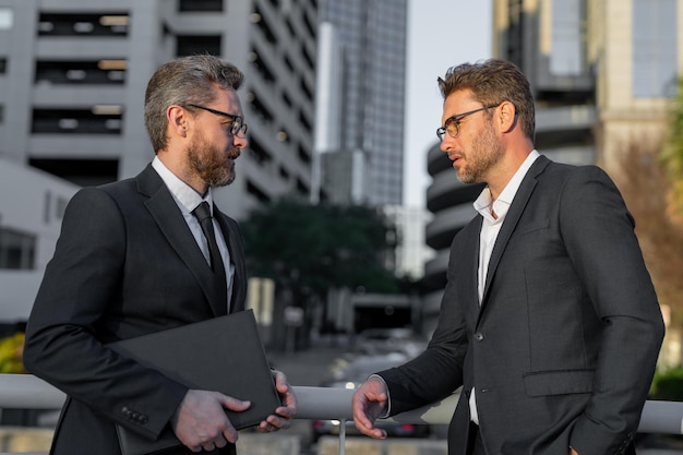 Réunion d'affaires en plein air deux hommes d'affaires en costume parlant de nouvelles financières debout dans la ville moderne