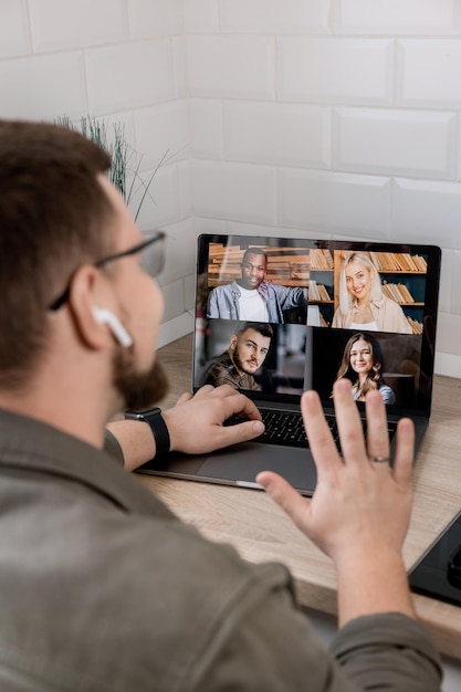 Photo réunion du matin en ligne un jeune homme utilise l'application sur son pc pour communiquer avec ses collègues