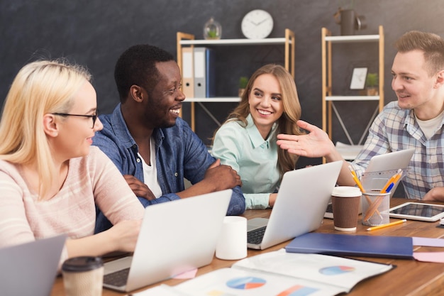 Réunion d'entreprise d'une équipe multiethnique. Jeunes gens joyeux remue-méninges, discutant d'un nouveau projet de démarrage au bureau, espace de copie