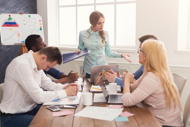 Réunion d'entreprise d'une jeune équipe avec une patronne. Femme en colère criant à ses travailleurs coupables d'échec. Discussion de bureau, communication avec les partenaires, espace de copie