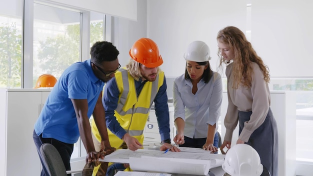 Réunion de l'équipe d'ingénierie diversifiée pour discuter du projet architectural et souriant à la caméra