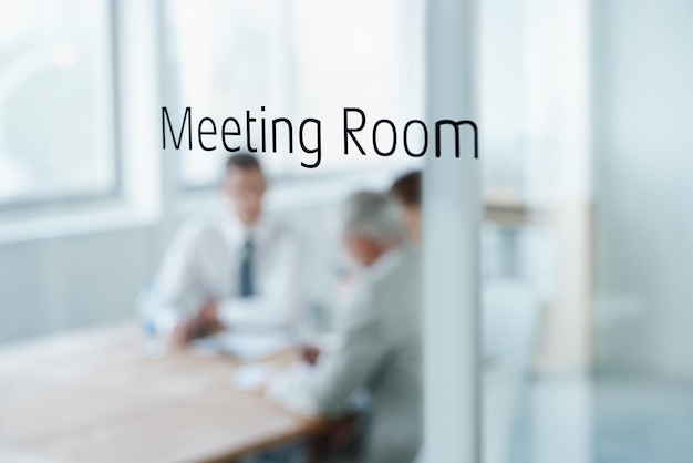 La réunion est en session Libre d'une salle de réunion de lecture de porte en verre avec des gens d'affaires flous dans la salle derrière