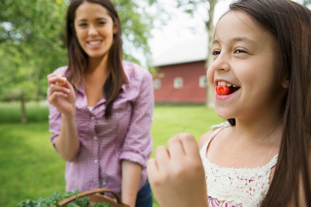 Une réunion de famille d'été dans une ferme Un enfant avec une cerise fraîche entre ses dents Une jeune femme watc