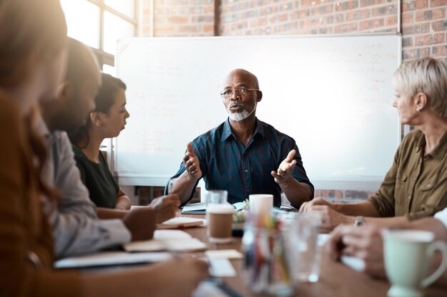 Réunion de gens d'affaires et leadership d'un homme noir au bureau parlant ou parlant Chef de la direction du travail d'équipe et collaboration de brainstorming professionnel masculin africain senior ou stratégie de planification dans le démarrage