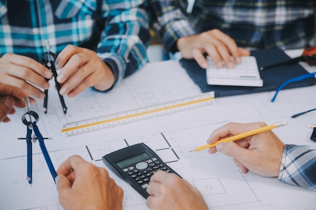 Réunion d'ingénieurs travaillant et pointant des dessins au bureau pour discuter d'outils d'ingénierie et de concept de construction