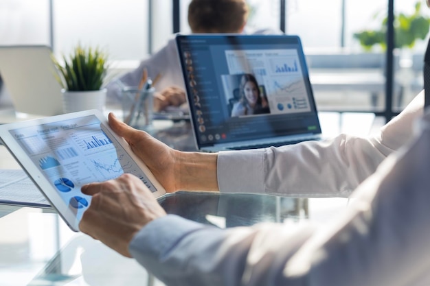 Réunion de personnes analysant des statistiques financières au bureau Groupe d'équipes commerciales ayant une vidéoconférence avec leur équipe sur une tablette numérique travaillant à distance à la maison