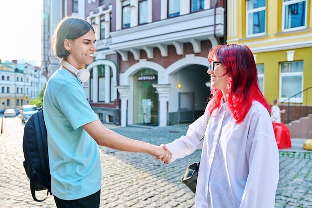 Réunion serrant la main d'amis adolescents masculins et féminins dans la rue de la ville