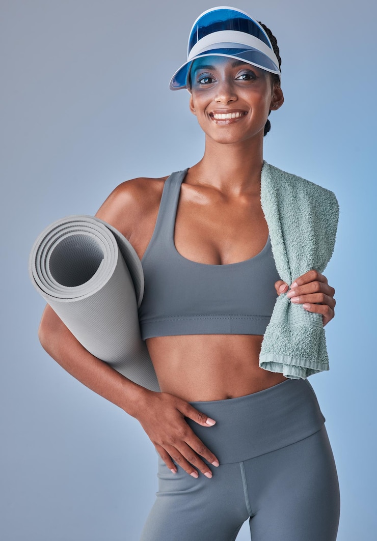 Photo une réussite de remise en forme en devenir prise de vue en studio d'une jeune femme en forme tenant une serviette et un tapis d'exercice sur un fond gris