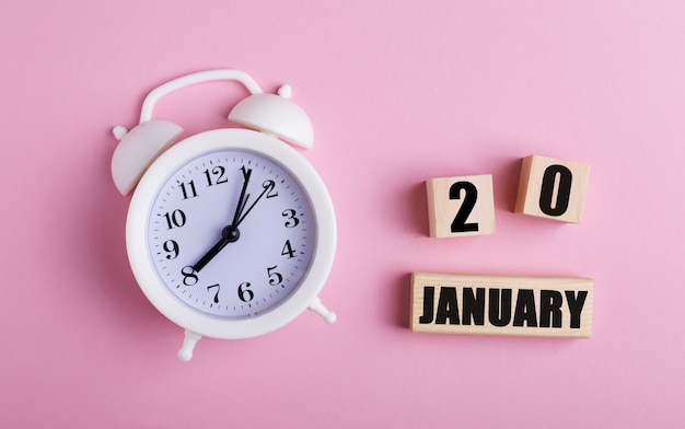 Photo réveil blanc et cubes en bois avec la date du 20 janvier sur rose