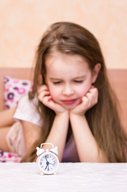 Réveil blanc se dresse sur la table d'une fille qui se réveille