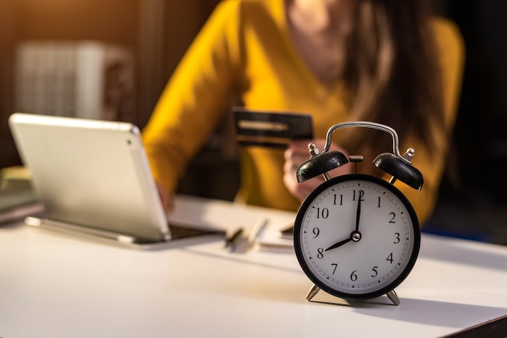 Photo réveil sur le bureau. entreprise travaillant dans un immeuble de bureaux moderne ou à domicile la nuit à l'aide d'un ordinateur portable.