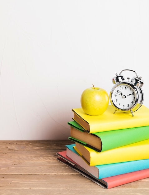 Photo réveil et pomme jaune sur une pile de manuels