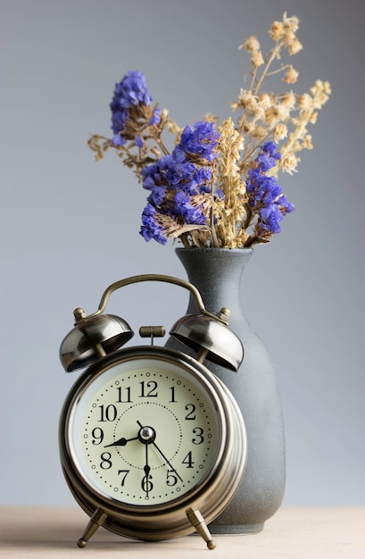 Réveil rétro et bouquet de fleurs sur une planche en bois