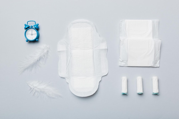 Réveil sonnant avec des tampons hygiéniques féminins et des serviettes hygiéniques menstruelles Concept médical des jours critiques de la femme et de la menstruation Hygiène quotidienne féminine Espace de copie