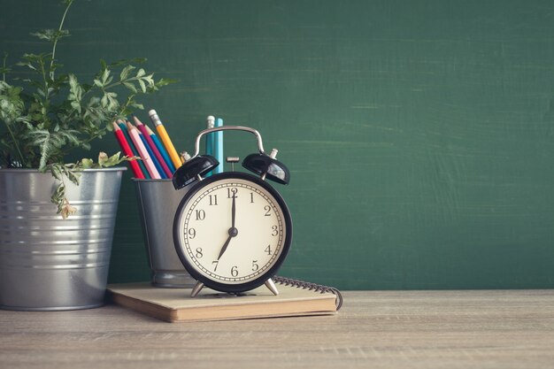 Réveil sur une table en bois sur fond de tableau noir dans la salle de classe