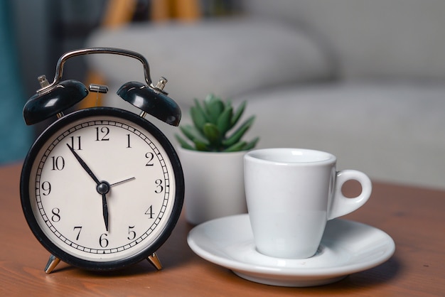 réveil avec une tasse de café aromatique sur la table