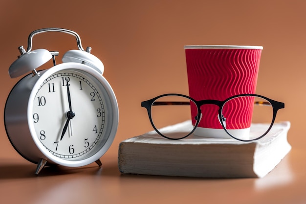 Réveil tasse de verres à café et livre matin concept