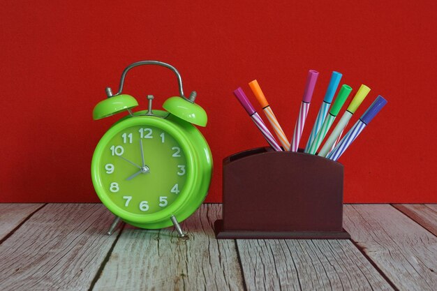 Photo un réveil vert et des stylos sur la table.
