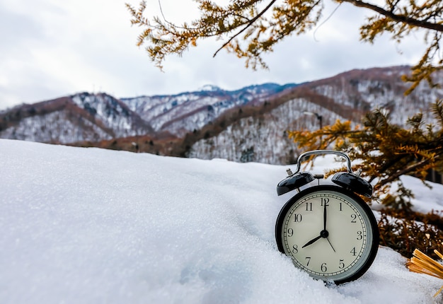 Réveil vintage sur la neige avec des arbres et des montagnes le matin.