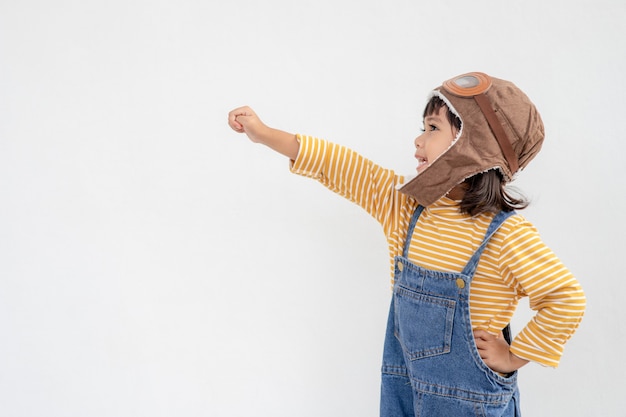 Rêves de vol ! petite fille enfant jouant avec un chapeau de pilote sur fond blanc