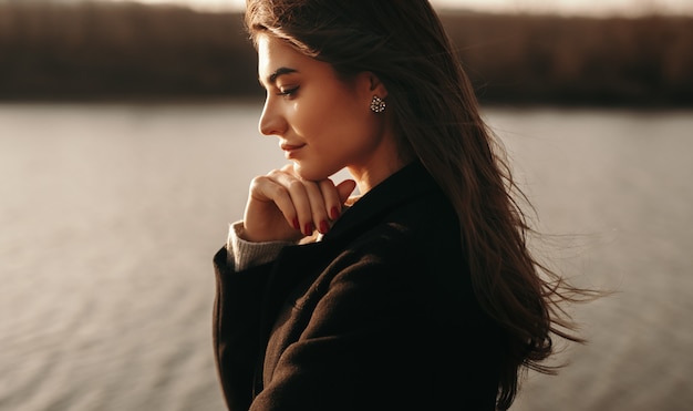 Rêveuse jeune femme debout près du lac