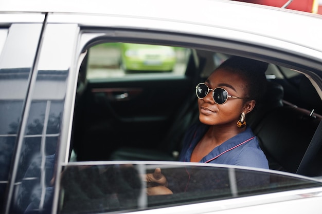 Riche femme africaine d'affaires sur des lunettes de soleil s'asseoir à la voiture suv et montrer la main de la fenêtre