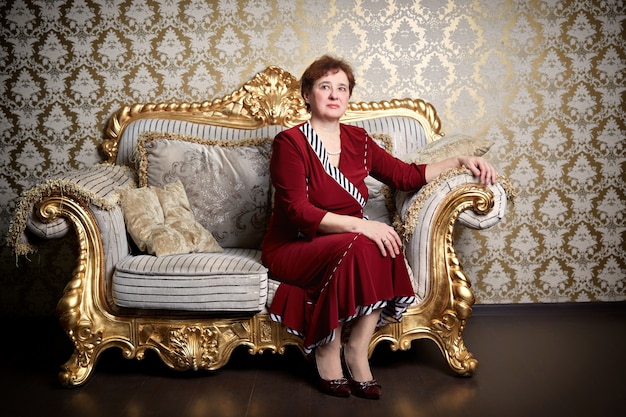 Photo riche femme âgée assise sur un canapé coûteux