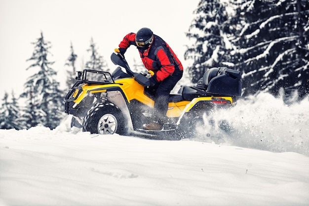 Rider conduisant dans la course de quad en hiver dans la forêt