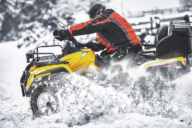 Rider conduisant dans la course de quad en hiver dans la forêt