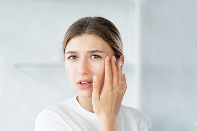 Rides des yeux vieillissement de la peau jeune femme touchant le visage