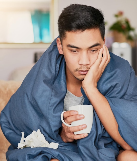 Rien d'amusant à propos de la grippe Photo d'un jeune homme enrhumé en convalescence à la maison