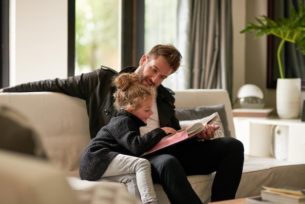 Photo rien de mieux que de se mettre à l'aise avec un livre ensemble photo recadrée d'un père lisant une histoire à sa fille à la maison