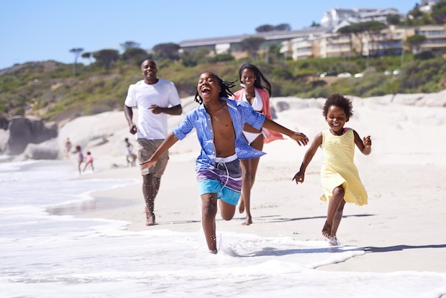 Rien ne vaut des vacances en famille Une jeune famille africaine heureuse courant énergiquement le long de la plage