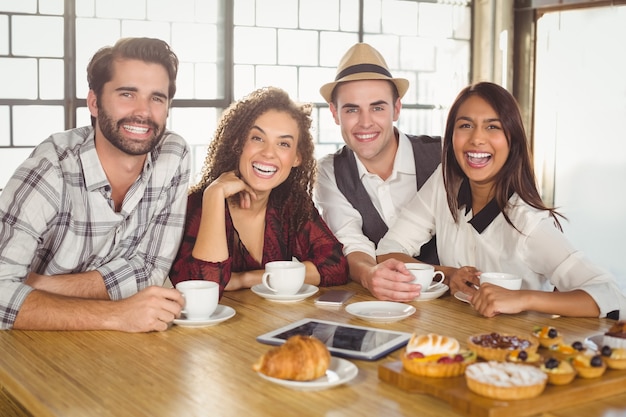 Rire des amis en appréciant le café et les friandises