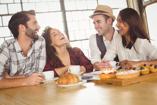 Rire des amis en appréciant le café et les friandises