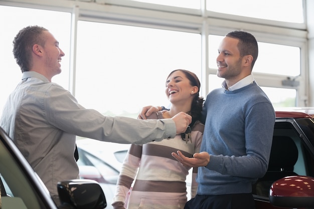 Rire couple recevant les clés d&#39;un vendeur