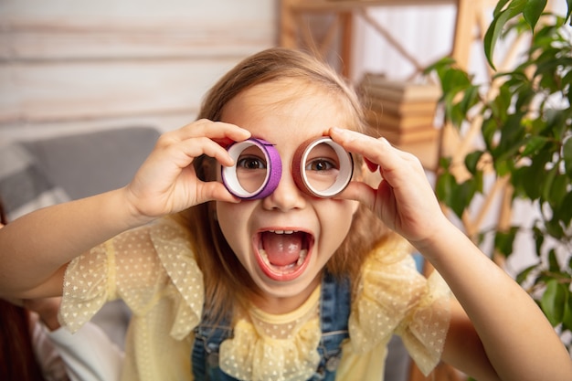 Rire. Enfants heureux, fille s'amusant dans la créativité de la maison. Un enfant heureux fabrique des jouets faits à la main pour les jeux