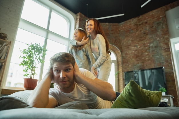 Rire. La famille passe du bon temps ensemble à la maison, a l'air heureuse et joyeuse. Maman, papa et fille s'amusent, se battent avec des oreillers. Convivialité, confort à la maison, amour, concept de relations.