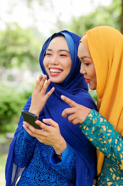 Rire des femmes musulmanes avec smartphone