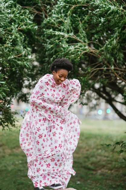 Rire fille afro-américaine enveloppée dans une feuille debout à la pierre à la nature.