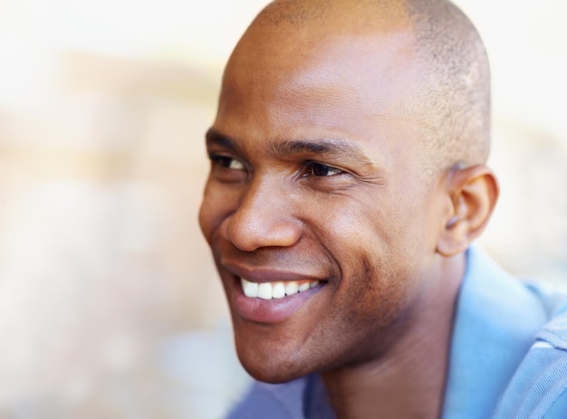 Photo rire heureux et visage d'un homme noir avec un sourire pour une attitude positive joyeux et joyeux à l'extérieur bonheur en gros plan et personne avec un fond flou pour une aventure relaxante et un état d'esprit insouciant