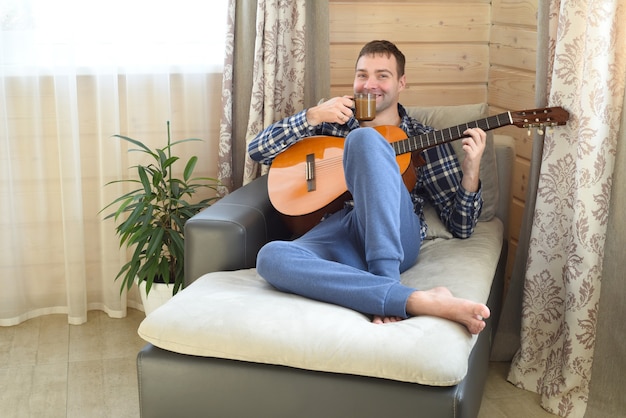 Rire homme jouant de la guitare et boire du café